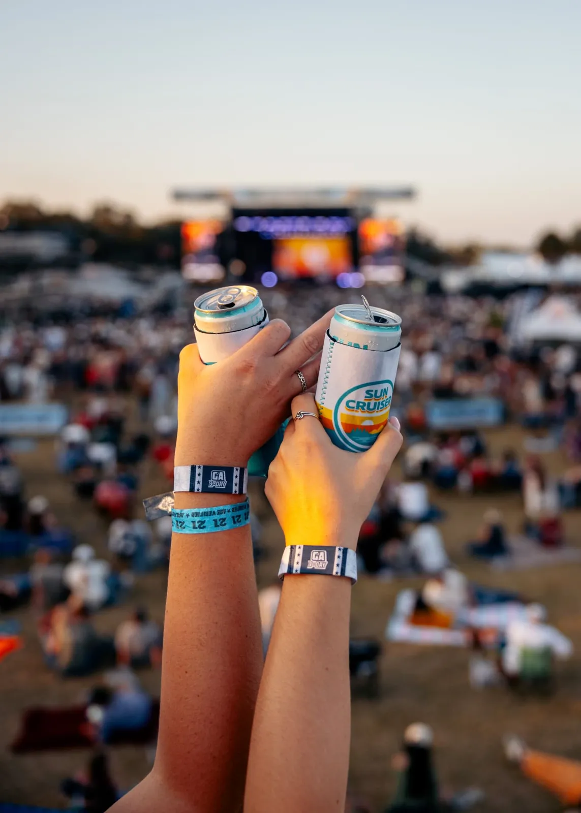Fans raising branded cans toward the main stage, a festival marketing activation