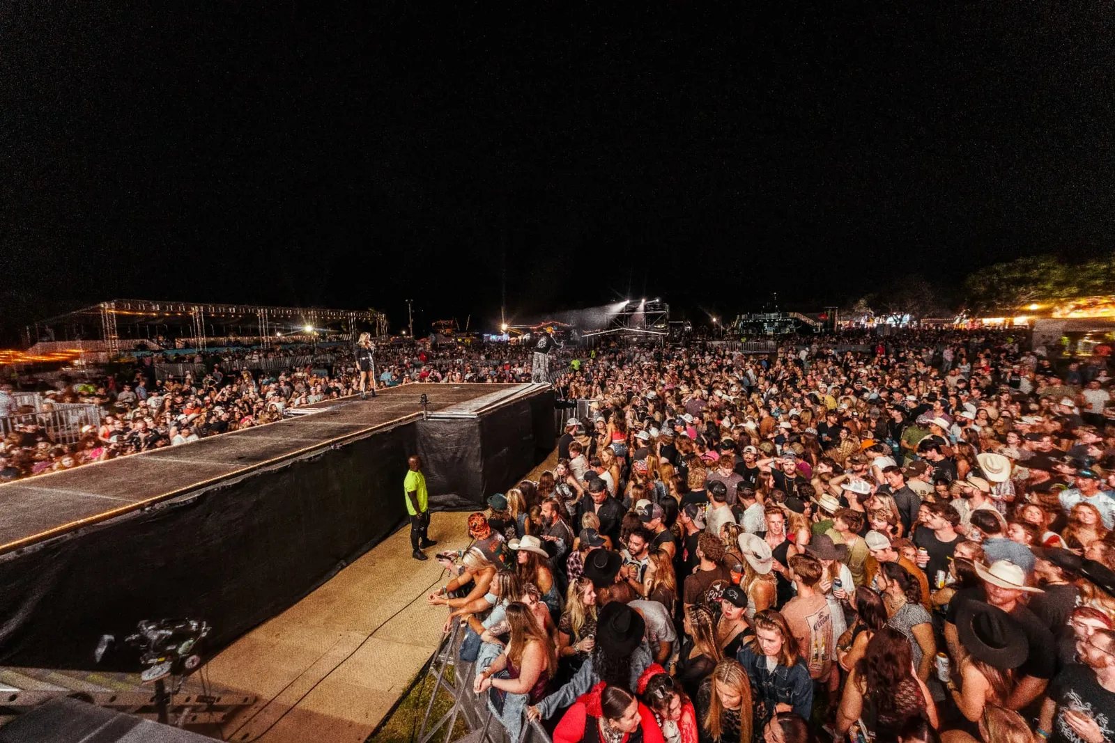 Packed festival crowd at the stage at night, reached by event sponsorship